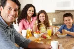 Alimentos con polifenoles como las frutas o el café previenen el síndrome metabólico Pareja con sus hijos desayunando café, zumo y frutas