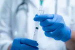 Explican características del síndrome posvacunación COVID y posibles causas Sanitario sostiene un vial de vacuna y una jeringa