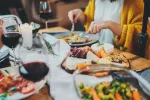 Una alta adherencia a la dieta mediterránea reduce el riesgo de cánceres asociados a la obesidad Grupo de personas come alimentos característicos de la dieta mediterránea