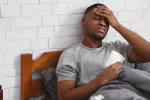 Enfermedad de origen desconocido causa decenas de muertos en el Congo Hombre negro en la cama con fiebre y dolor de cabeza se toca la frente