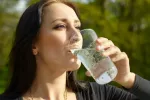 Agua con gas, ¿es saludable? Beneficios, mitos y contraindicaciones Mujer bebiendo un vaso de agua con gas