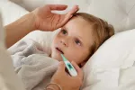 Hallan la causa del síndrome pos-COVID MIS-C que ataca a los niños Madre toma la temperatura a su hija pequeña enferma en la cama