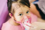 Identifican 5 casos de infección por enterovirus C105 en España Mujer coloca un inhalador a una niña pequeña con infección respiratoria