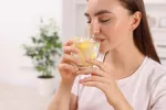 Agua caliente con limón en ayunas, ¿de verdad es beneficioso? Mujer bebiendo un vaso de agua tibia con limón