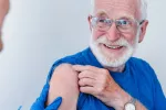 La vacuna contra la culebrilla reduce el riesgo de demencia en adultos mayores Un anciano sonriente se prepara para recibir una vacuna