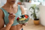 Alimentos que cuidan la microbiota alivian la fibromialgia Mujer deportista toma un bol de lácteos, frutas y cereales