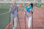 Caminar regularmente a un paso rápido puede evitar las arritmias cardíacas Un hombre y una mujer mayores sonríen mientras practican marcha nórdica