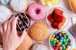 La ingesta de alimentos ricos en grasas y azúcares afecta al rendimiento cognitivo y la memoria espacial Mano de mujer coge un donut de chocolate de una variedad de comida rápida