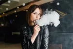 El fármaco oral vareniclina ayuda a los jóvenes a dejar de vapear nicotina Chica joven mira a la cámara mientras expulsa vapor tras aspirar su e-cigarrillo