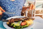 Las mujeres posmenopáusicas que siguen la dieta mediterránea tienen menos riesgo de cáncer de mama Una mujer se dispone a comer un plato de pescado y verduras