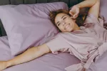Dormir pocas horas sin efectos negativos se debería a una mutación genética Una mujer se despierta feliz en su cama tras haber dormido bien