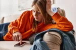 Malestar emocional crece entre los adolescentes españoles Adolescente triste mirando su smartphone desde el sofá