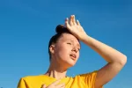 El calor afecta negativamente a una mujer Mujer joven bajo el sol se toca el pecho y la frente con gesto de agobio