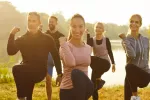 Personas haciendo ejercicio junto a su entrenadora junto a un lago Grupo de personas hace ejercicio al aire libre