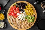 Garbanzos y frijoles negros forman parte de una ensalada Plato de ensalada con tomates, frijoles negros, garbanzos, maíz y queso
