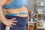 Mujer con obesidad mide su perímetro abdominal Mujer obesa utiliza cinta métrica para medir su perímetro abdominal