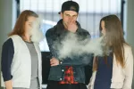 Chicas adolescentes usan dispositivos para vapear desechables Dos chicas adolescentes vapean alrededor de un joven que se tapa la nariz