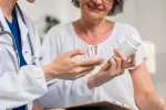 Doctora muestra frasco pastillas a una mujer mayor