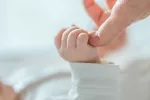 Tratamiento reduce mortalidad por neumonía en bebés con VIH Bebé cogiéndole el dedo a su madre