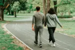 Objetivo de 7000 pasos diarios para mejorar la salud Una pareja en chándal camina de espaldas por un parque