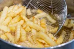 Patatas fritas en aceite Patatas friéndose en aceite hirviendo
