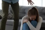 Mujer joven sufre maltrato psicológico por parte de su pareja Mujer asustada sentada en el suelo mientras un hombre la amenaza