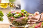 Ensalada típica de la dieta mediterránea es aliñada con aceite de oliva Una mujer aliña una ensalada de estilo mediterráneo con aceite de oliva
