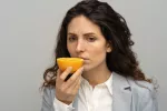 Mujer morena no es capaz de oler una naranja que sostiene con su mano