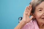 Pérdida de auditiva y riesgo de aislamiento Mujer anciana con la mano en la oreja mostrando dificultades para oír