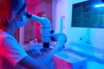 Científica en el laboratorio analiza óvulos humanos Una embrióloga mira a través del microscopio en el laboratorio