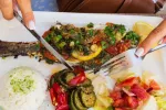 Pescado y verduras típicos de la dieta mediterránea listos para comer Manos de mujer cortan alimentos de un menú típico de la dieta mediterránea