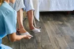 Concepto de fragilidad en la tercera edad ligado a discapacidad Enfermera ayudando a una anciana a poner bien los pies en su silla de ruedas