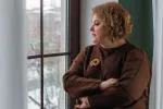 Mujer de mediana edad con obesidad y aspecto triste Mujer obesa de mediana edad mira por la ventana con gesto triste