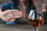 Mujer rechaza una copa de alcohol Mujer hace un gesto de rechazo con la mano a una copa de alcohol
