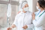 Paciente con cáncer de mama recibe quimioterapia junto a su médico Mujer con cáncer recibe quimioterapia animada por su doctora