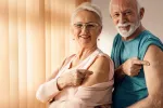 Pareja de adultos mayores sonrientes tras vacunarse contra el COVID Mujer y hombre mayores sonríen y muestran su brazo tras haberse vacunado