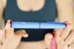 Mujer muestra una pluma de Ozempic y una cinta métrica Una mujer con ropa deportiva sujeta una pluma con semaglutida