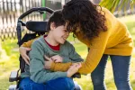 Niño en silla de ruedas es atendido por su madre Mujer atiende a su hijo en silla de ruedas