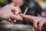 Manos de adolescentes pasándose un porro de marihuana en la calle