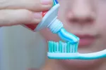 Cómo elegir la pasta de dientes adecuada a tus necesidades Un joven poniendo un poco de pasta de dientes sobre el cepillo dental