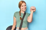 Mujer joven con bolsa de entrenamiento sostiene un cerebro de plástico sonriendo