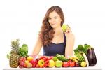 Mujer sentada a una mesa con frutas y verduras