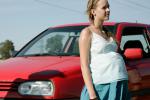 Joven embarazada de pie junto a un vehículo