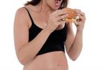 Mujer embarazada comiendo una hamburguesa