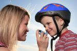 Una mujer ofrece el inhalador a su hijo antes de que esté monte en bicicleta