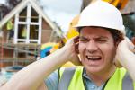 Un obrero de la construcción se tapa los oídos para protegerse de un ruido intenso