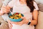 Mujer embarazada tomando comida saludable