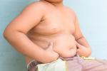 Niño obeso se pellizca los michelines del abdomen