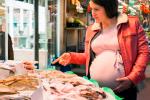 Mujer embarazada comprando pescado para tomarlo