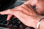 Persona mayor escribiendo en un teclado de ordenador